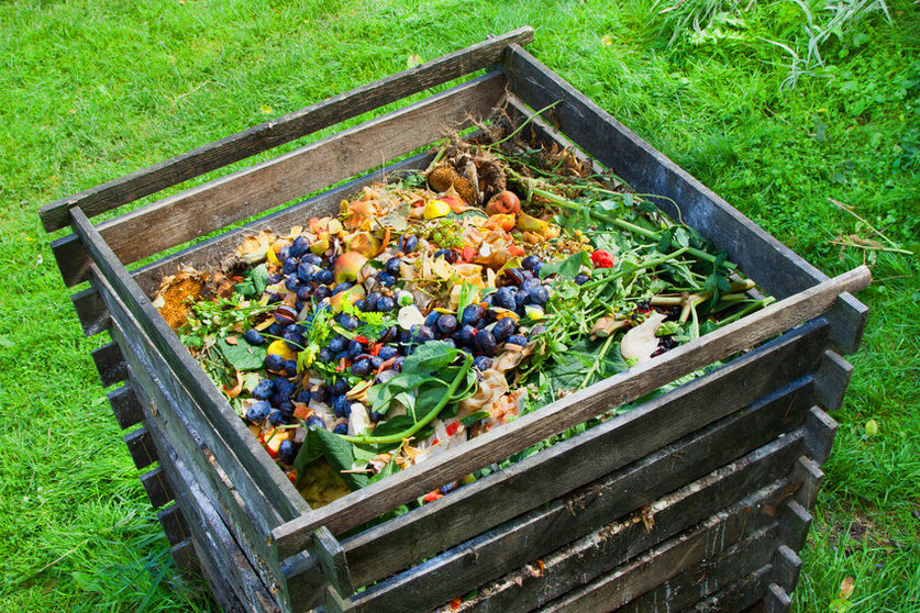 Compost bin in the garden. Composting pile of rotting kitchen fruits and vegetable scraps